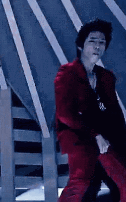 a man in a red suit is standing in front of a set of stairs