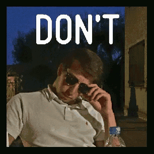 a man wearing sunglasses is sitting in front of a sign that says don t
