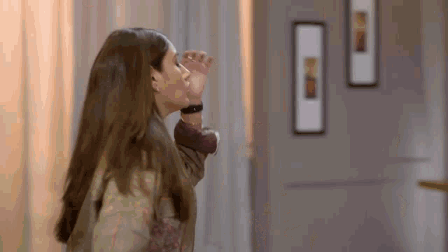 a woman with long hair is standing in a room with a door .