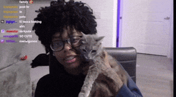 a man wearing glasses is holding a cat in front of a computer screen