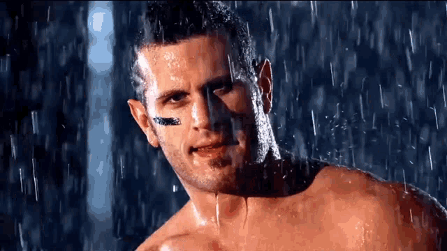 a shirtless man is taking a shower in the rain and has a football on his face .