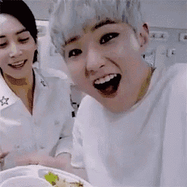 a man and a woman are sitting at a table with a plate of food and smiling .