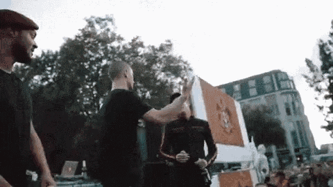 a man is giving a high five to another man while standing in front of a crowd .