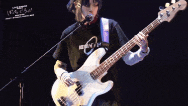 a person playing a bass guitar in front of a microphone and a sign that says live stage