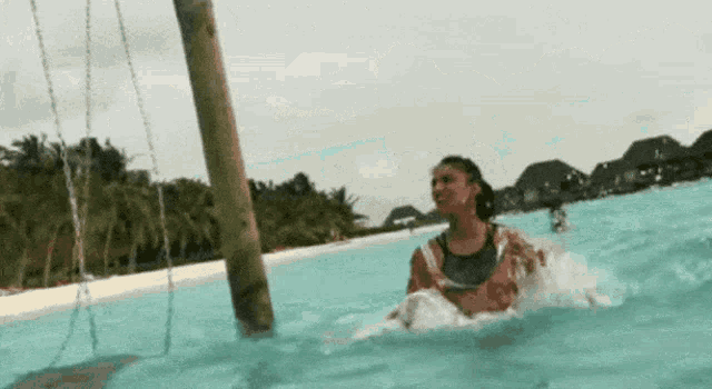 a woman is riding a swing in a pool .