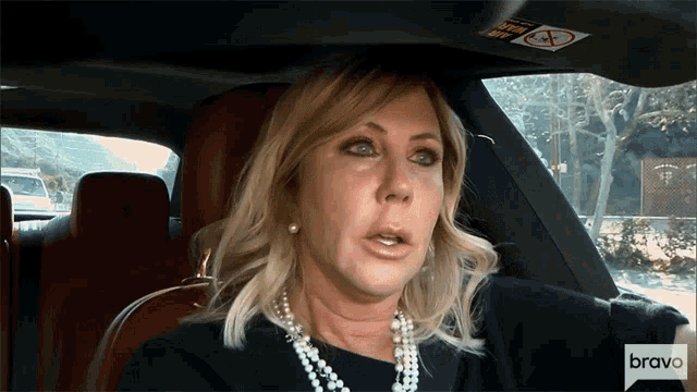 a woman is sitting in a car with the word bravo on the bottom