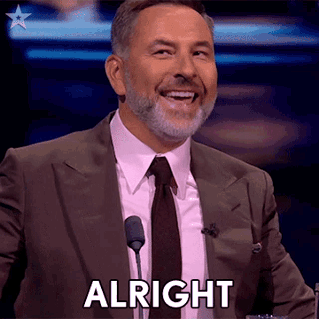a man in a suit and tie is giving a speech and says alright