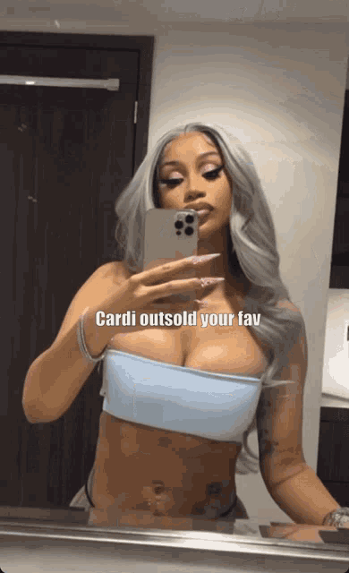 a woman is taking a picture of herself in a mirror with the caption cardi outsold your fav