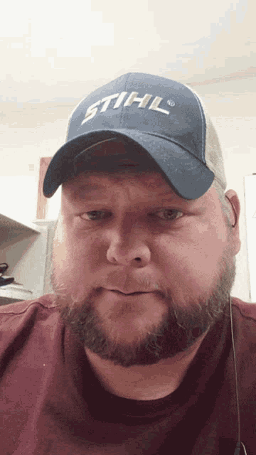 a man with a beard is wearing a blue stihl hat