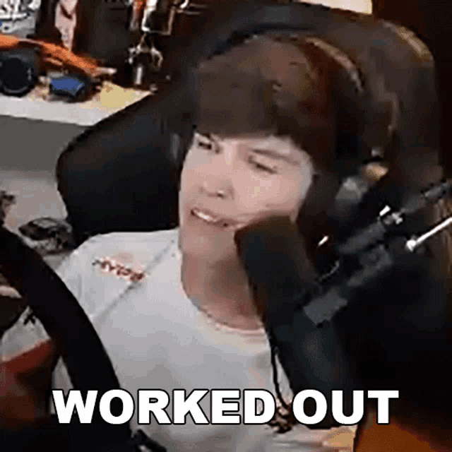 a man wearing headphones is sitting in front of a microphone with the words `` worked out '' above him .