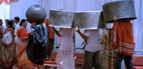 a group of people are carrying pots on their heads