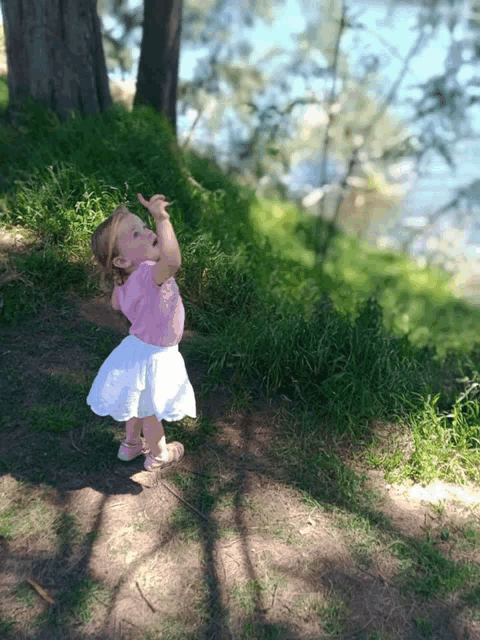 a little girl in a pink shirt and white skirt