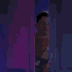a man is peeking out from behind a door in a dark room .