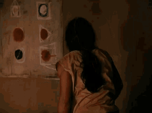 a woman is sitting in front of a wall with a drawing on it .