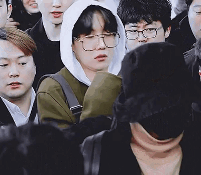 a group of people including a man wearing glasses and a hoodie