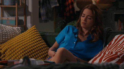 a woman in a blue shirt laying on a couch