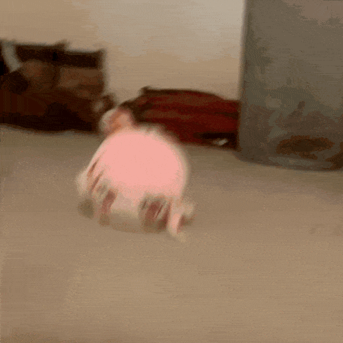 a pink stuffed animal is laying on the floor in front of a trash can