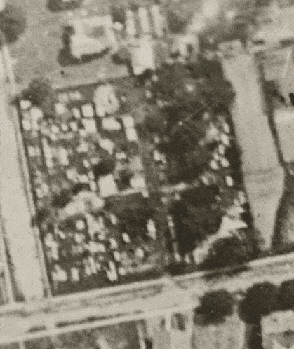 a black and white photo of an aerial view of a city with a lot of buildings and trees .