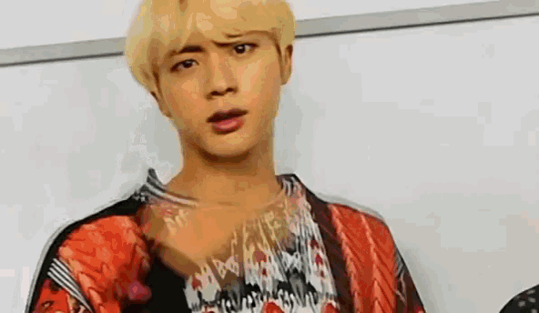 a close up of a person making a funny face while wearing a colorful shirt .