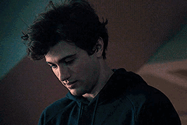 a young man wearing a black hoodie is looking down at something .