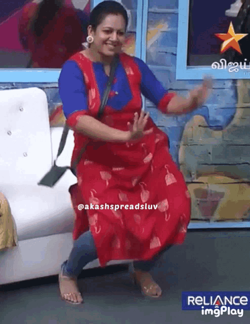 a woman in a red dress is dancing in front of a sign that says reliance