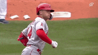 a baseball player wearing a red helmet and gloves is running on a field .