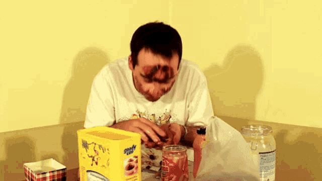 a man sitting at a table with a box of kellogg 's cereal on it