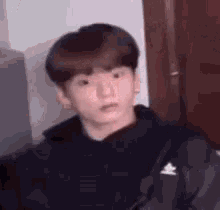 a young man in a black hoodie is making a funny face and looking at the camera .