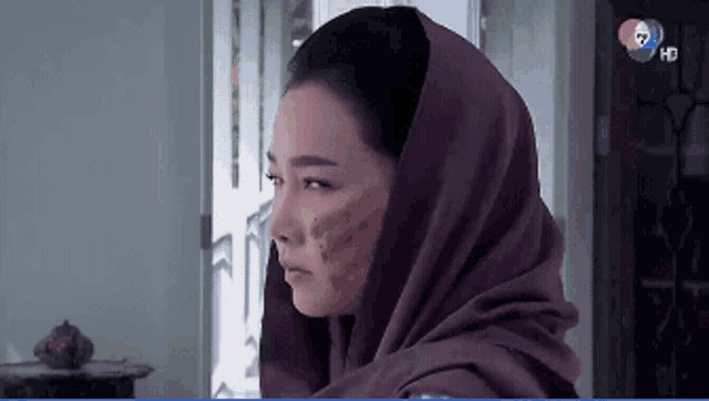 a woman wearing a scarf around her head has a purple scarf around her head