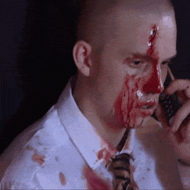 a man with blood on his face talking on a phone