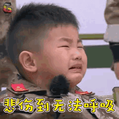 a little boy in a military uniform is crying with chinese writing on the bottom .
