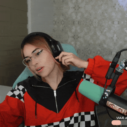 a woman wearing headphones sits in front of a microphone with viaje written on the bottom