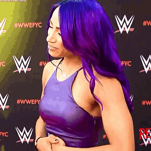 a woman with purple hair is standing in front of a wall that says wwe .