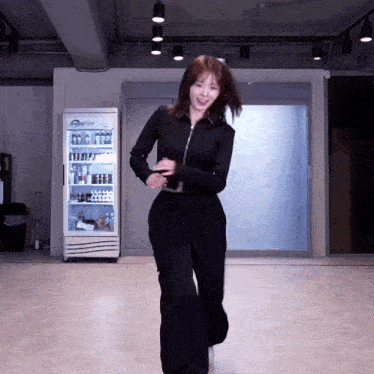 a woman is dancing in front of a fridge that says ' tcl ' on it