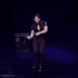 a man in a black shirt is standing on a stage with a microphone .