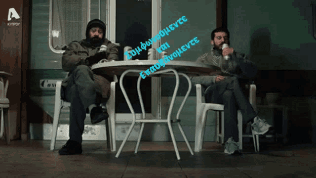 two men sit at a table with a sign that says a