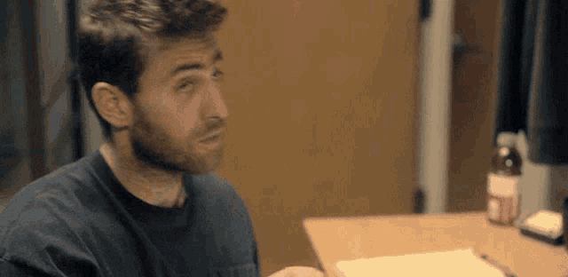 a man is sitting at a table with a notebook and a bottle of soda .