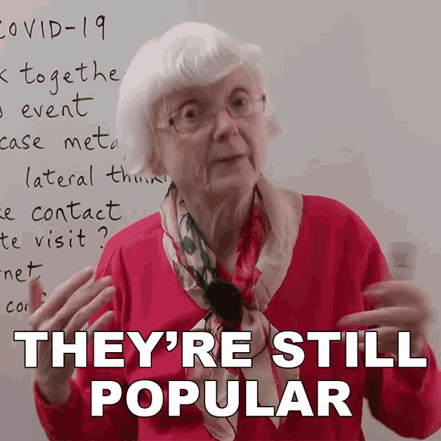 an elderly woman says they 're still popular in front of a whiteboard with covid-19 written on it