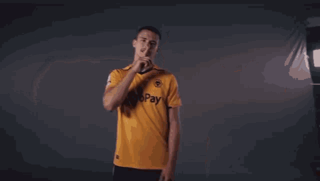 a man in a yellow astropay shirt is standing in front of a sign that says pipe down