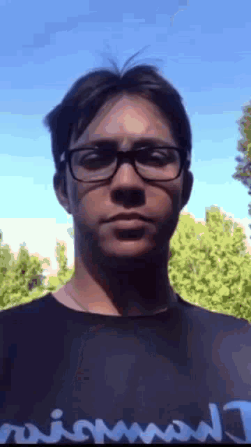 a man wearing glasses and a shirt that says ' mismad ' on it