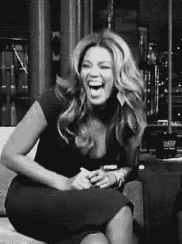 a woman is sitting on a couch laughing .