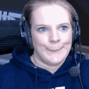 a woman wearing headphones and a microphone is making a funny face