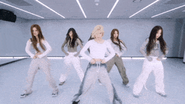 a group of young women are dancing in a room