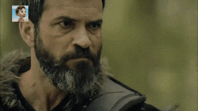 a man with a beard is holding a sword in a forest