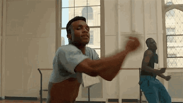 a man without a shirt is dancing in a dance studio with another man .