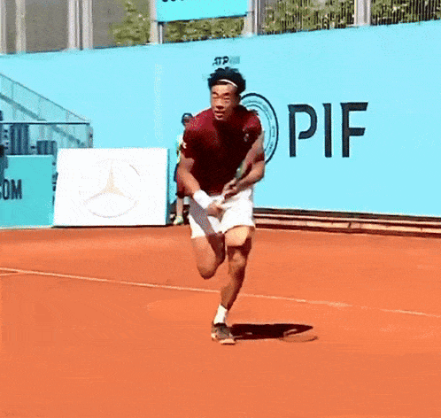 a man is running on a tennis court in front of a wall that says pif