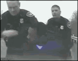 a man is being arrested by a group of police officers with the letter b on their uniforms .