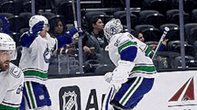 a group of hockey players are celebrating a goal in front of a nhl logo