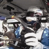 a man wearing a helmet and gloves is driving a racing car