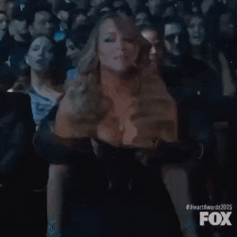a woman in a black dress is sitting in the audience at a concert .